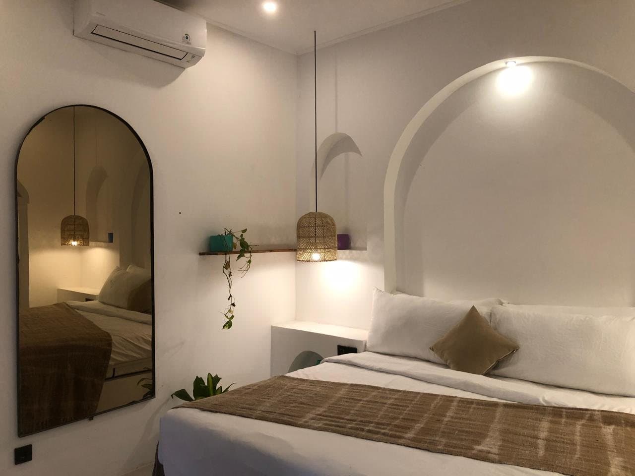 Bedroom with arched mirror, rattan pendants and a sculpted arch above the bed