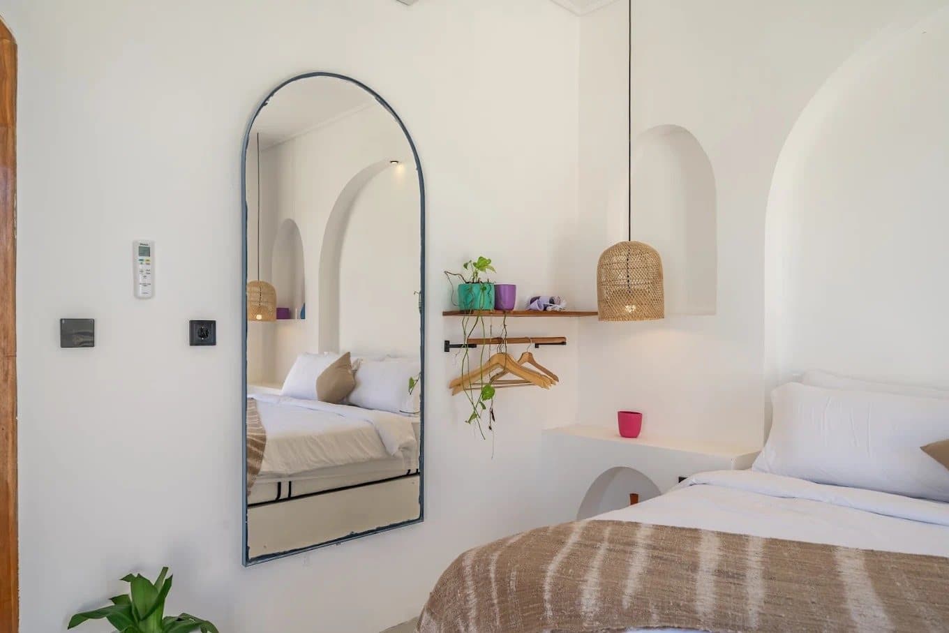 Full-length arched mirror and rattan pendant beside the bed