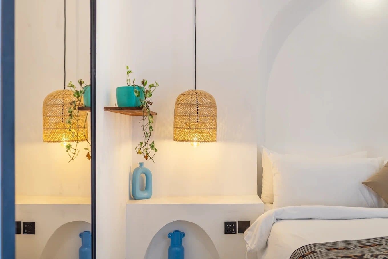 Rattan pendant lights and plants above a bedside niche