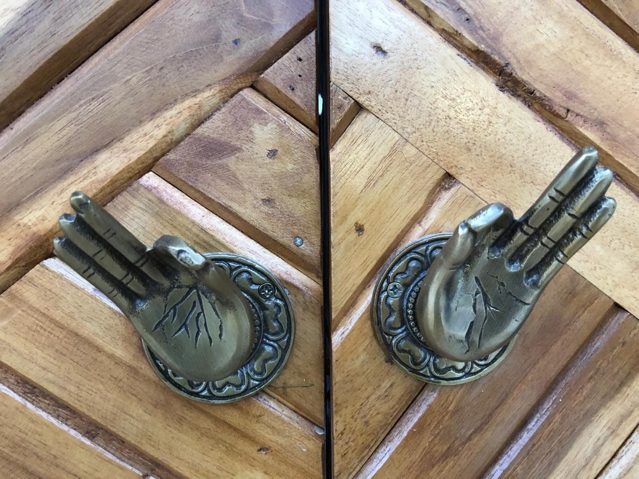 Hand-shaped brass handles on chevron teak doors