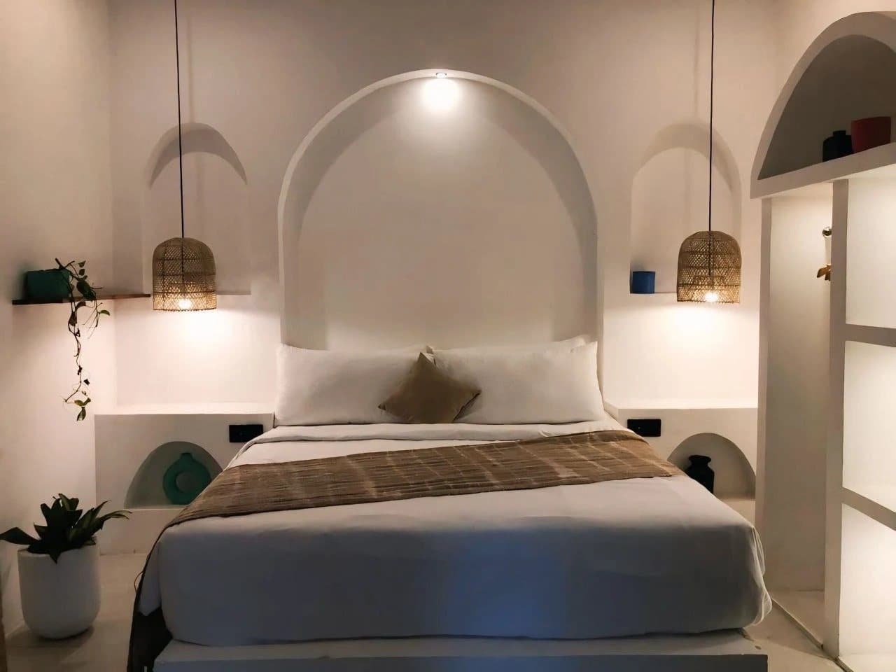 Bed set in a sculpted arch with woven pendant lights