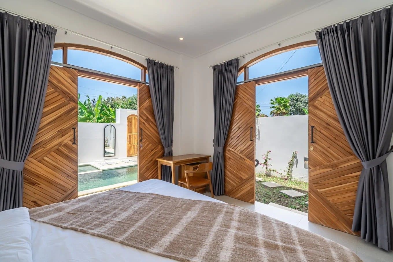 Bedroom with tall teak doors opening straight onto the pool