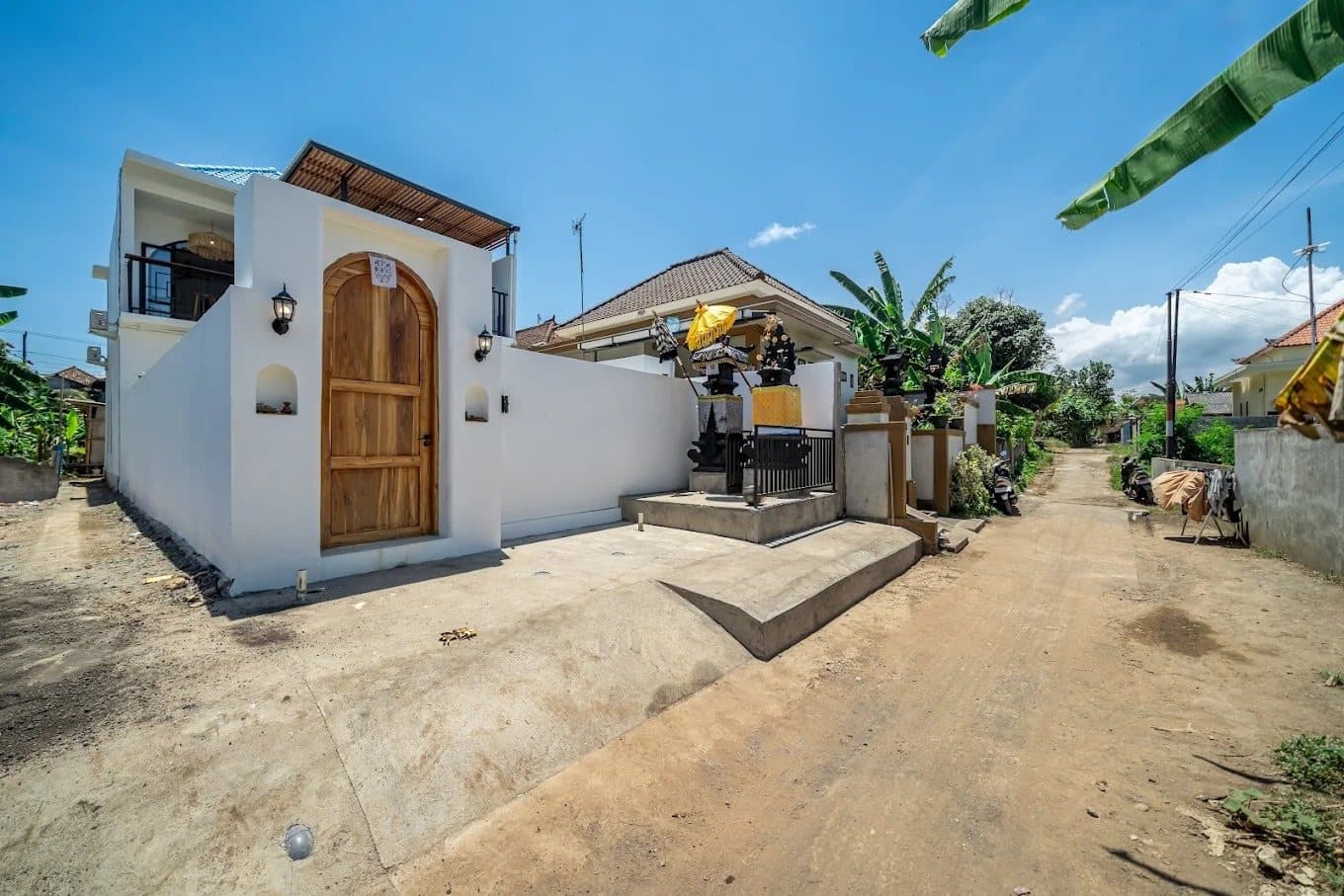 Front of the villa with an arched wooden gate on a quiet village lane