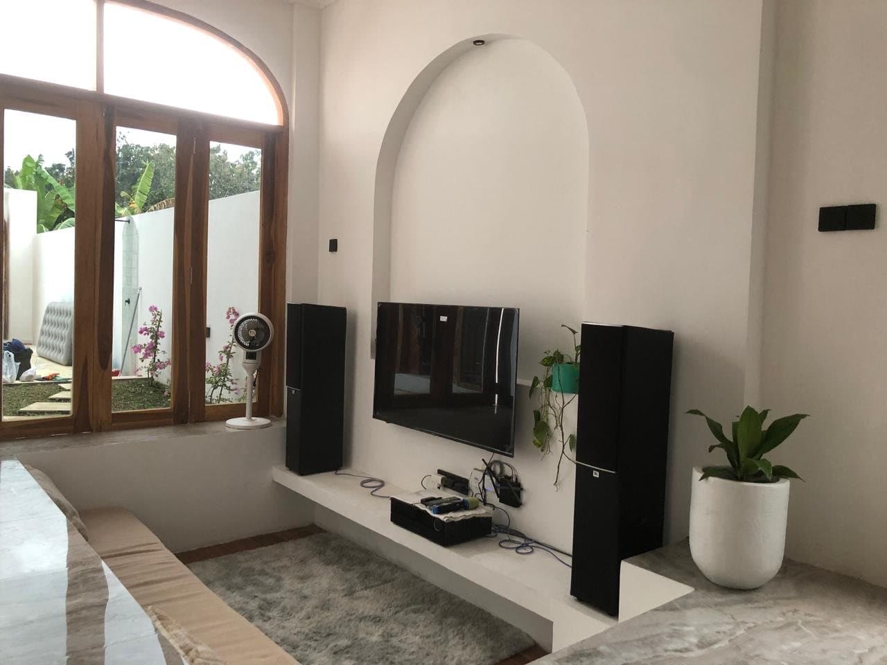 Living room with TV, tall speakers, sofa and arched garden window